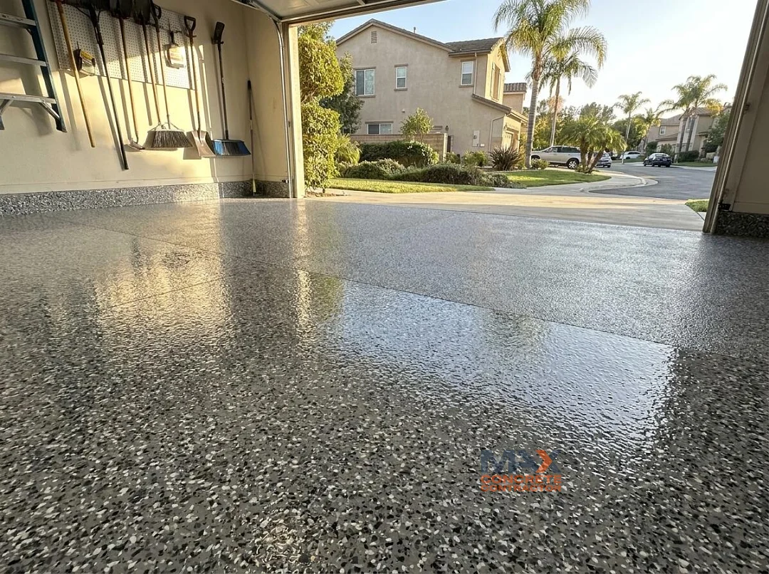 Matching flake pattern connecting an epoxy garage floor and a polyaspartic driveway coating in Irvine, CA