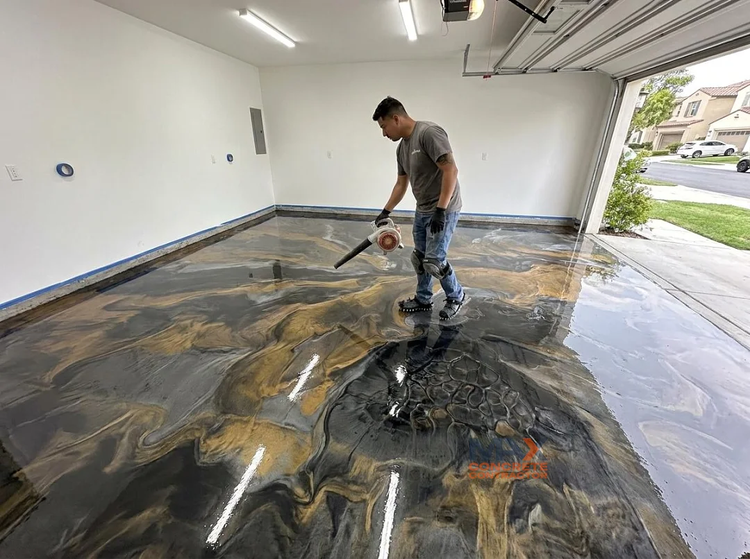 Installer creating a marbled pattern while applying a metallic epoxy floor coating in a garage in Irvine, CA